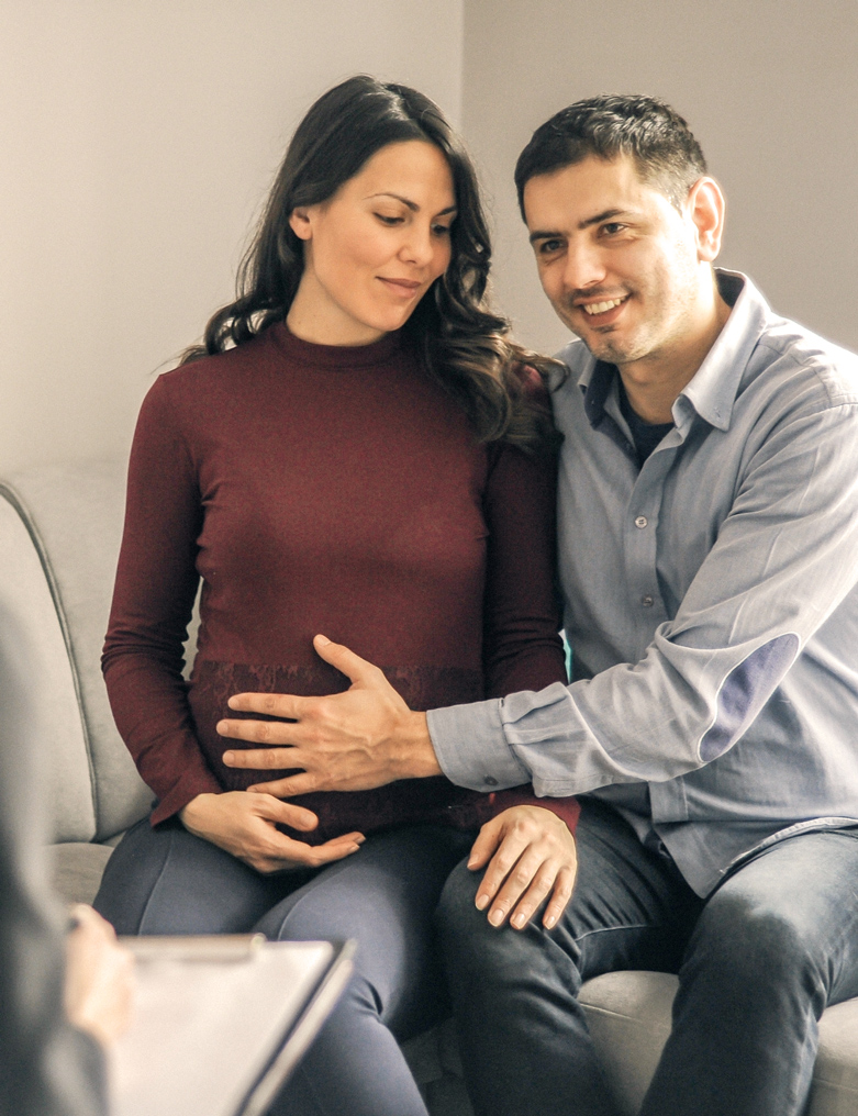 Couple in a counselling session where man has his hand over woman's pregnant belly